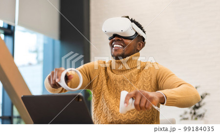 An excited black man exploring virtual reality in an office An excited black man exploring virtual reality in an office 99184035