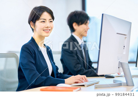 オフィスでパソコンを操作する笑顔のミドルビジネスウーマン 99184431