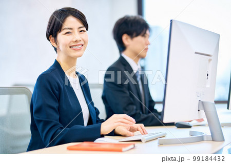 オフィスでパソコンを操作する笑顔のミドルビジネスウーマン 99184432