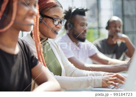 Smiling beautiful African American woman working in call center with diverse team 99184723