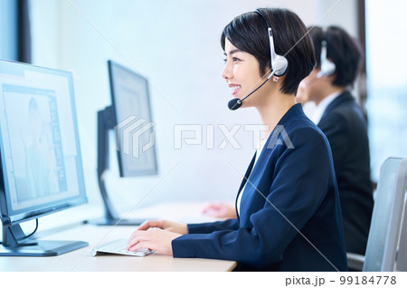 オフィスでヘッドセットをつけて対応するオペレーターの女性 オフィスでヘッドセットをつけて対応するオペレーターの女性 99184778