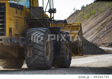A front end loader machine tipping sand in a quarry 99184795