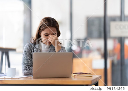 Young businesswoman working on laptop stressed has a headache and thinks hard from work at the office Young businesswoman working on laptop stressed has a headache and thinks hard from work at the office 99184866