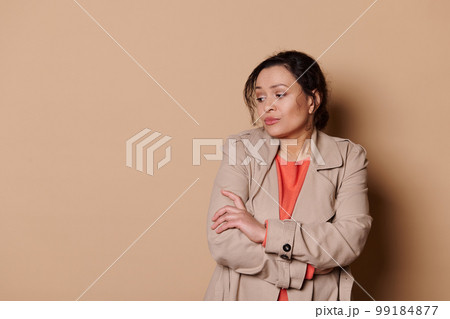 Unsure woman with folded hands looks away, apprehensive, expressing insecurity and worry over beige background. Ad space Unsure woman with folded hands looks away, apprehensive, expressing insecurity and worry over beige background. Ad space 99184877