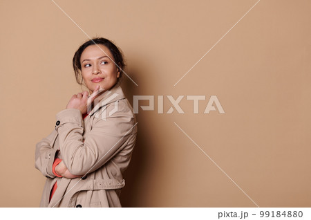 Pensive pretty woman putting index finger on her chin and dreamily looking aside, reasoning. Isolated beige abckground Pensive pretty woman putting index finger on her chin and dreamily looking aside, reasoning. Isolated beige abckground 99184880