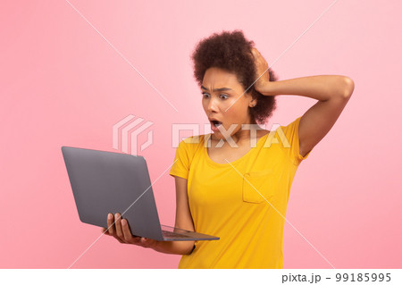 Sad shocked young african american curly woman with open mouth look at laptop, find mistake Sad shocked young african american curly woman with open mouth look at laptop, find mistake 99185995