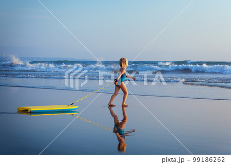 Young surfer girl with bodyboard has fun on sea beach 99186262