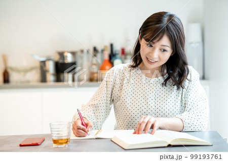 ダイニングテーブルで勉強するミドルの女性 99193761