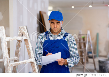 Young foreman checks the completed construction work and signs the documents 99193770