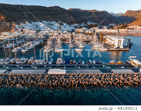 Luxury yachts docked by the golden coast of Spain during magical sunset lights. Luxury holiday concept. Aerial view. 99194011