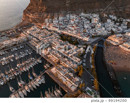 Puerto de Mogan fishing town aerial view at sunset. Traditional colorful buildings with many fishing boats at Gran Canaria, Canary Islands, Spain 99194200