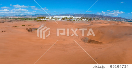 Panoramic aerial scene of the Maspalomas Dunes in Playa del Ingles, Maspalomas, Gran Canaria, Spain. Endless desert sands. Magical safari dunes. Panoramic aerial scene of the Maspalomas Dunes in Playa del Ingles, Maspalomas, Gran Canaria, Spain. Endless desert sands. Magical safari dunes. 99194734