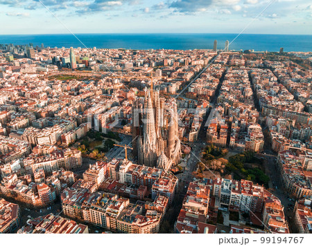 Aerial view of Barcelona City Skyline and Sagrada Familia Cathedral at sunset. Eixample residential famous urban grid. Cityscape with typical urban octagon blocks Aerial view of Barcelona City Skyline and Sagrada Familia Cathedral at sunset. Eixample residential famous urban grid. Cityscape with typical urban octagon blocks 99194767