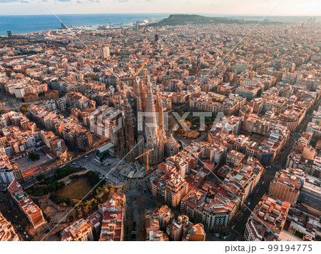Aerial view of Barcelona City Skyline and Sagrada Familia Cathedral at sunset. Eixample residential famous urban grid. Cityscape with typical urban octagon blocks Aerial view of Barcelona City Skyline and Sagrada Familia Cathedral at sunset. Eixample residential famous urban grid. Cityscape with typical urban octagon blocks 99194775