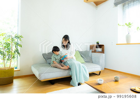 リビングでスマホを見る親子 99195608