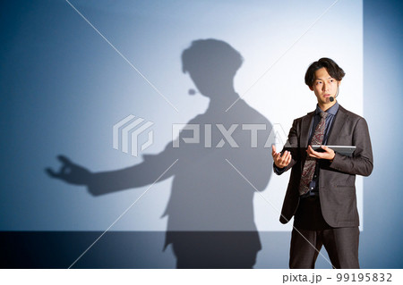 スクリーンを背景にしてスピーチをする若いビジネスパーソン 99195832