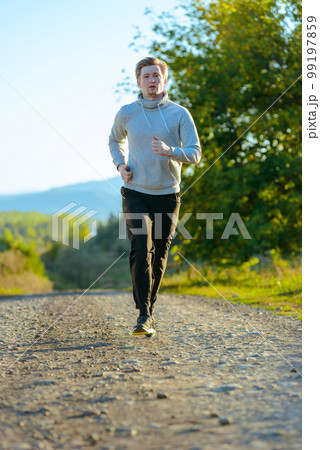 Man jogging in rural nature at beautiful summer day. Sport fitness model caucasian ethnicity training outdoor. Man jogging in rural nature at beautiful summer day. Sport fitness model caucasian ethnicity training outdoor. 99197859