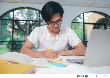 Young Asian male student is preparing to reading a books for exams at university. 99198072