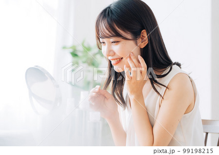 鏡でお肌のチェックをする笑顔の女性 鏡でお肌のチェックをする笑顔の女性 99198215
