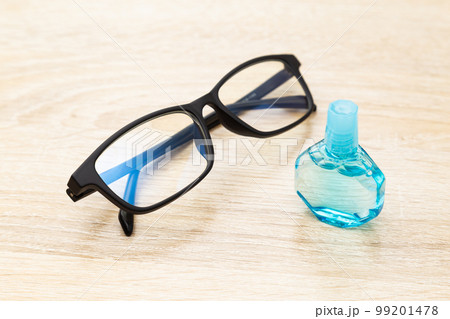 机に置かれた目薬と眼鏡 99201478