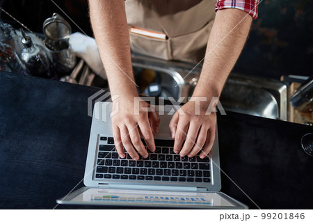 cropped image of a male bartender using a laptop. cropped image of a male bartender using a laptop. 99201846