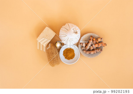 Top view of herbal compress ball with Thai herbal, turmeric, essential oil and bar soap on orange pastel background. Spa background concept. Top view of herbal compress ball with Thai herbal, turmeric, essential oil and bar soap on orange pastel background. Spa background concept. 99202193