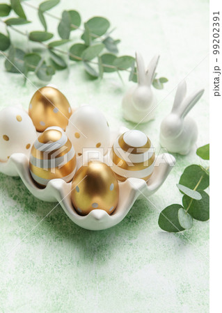 Easter decor. Golden Easter eggs on a ceramic holder and decorative rabbits. Easter decor. Golden Easter eggs on a ceramic holder and decorative rabbits. 99202391