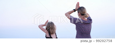 Mother and daughter do yoga meditate in lotus position on beach. 99202758