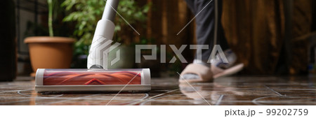 Cordless vacuum cleaner with turbo brush cleans tiles in living room 99202759