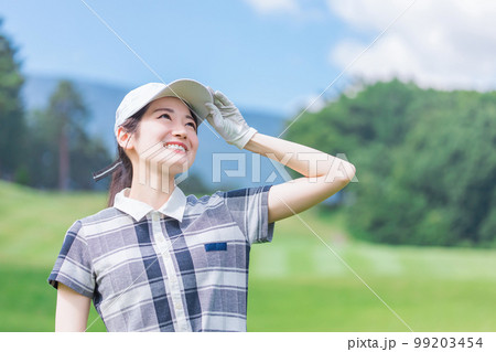 ゴルフ場でゴルフをするゴルフウェアを着たゴルファーの女性 ゴルフ場でゴルフをするゴルフウェアを着たゴルファーの女性 99203454