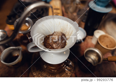Man pouring hot water on ground coffee with paper filter to making a drip coffee Man pouring hot water on ground coffee with paper filter to making a drip coffee 99203776