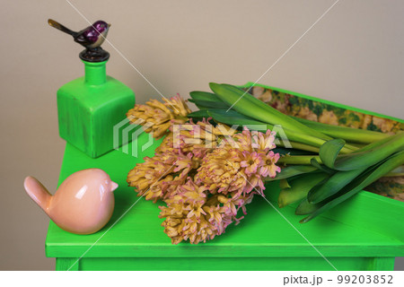 Bouquet of yellow-orange hyacinths on a green stand with spring decorations 99203852