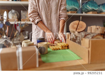 Close up of woman is packing handmade candles for selling in own home decor studio Close up of woman is packing handmade candles for selling in own home decor studio 99205231
