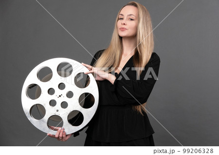 A young woman movie executive is holding an old film reel A young woman movie executive is holding an old film reel 99206328