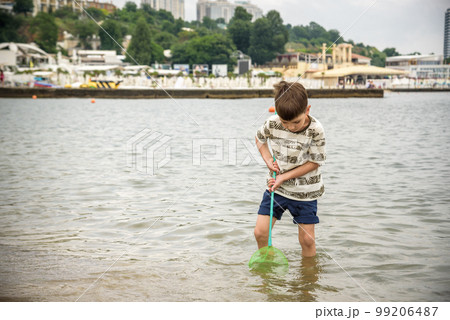 One little boy alone exploring the beach at low tide walking towards the sea coast. happy childhood concept 99206487