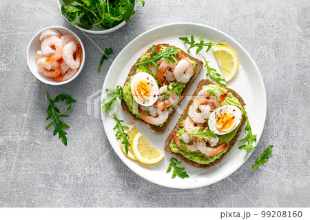 Toast with shrimps, avocado guacomole, arugula and boiled egg, top view 99208160