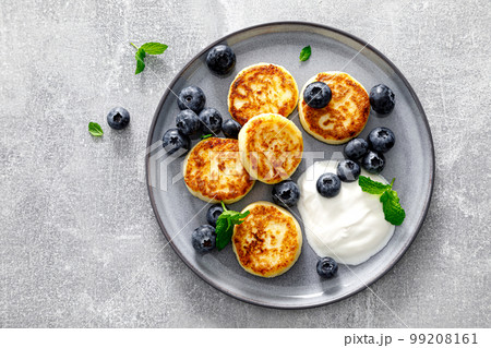 Cottage cheese fritters with fresh blueberry and yogurt for breakfast, copy space, view from above 99208161