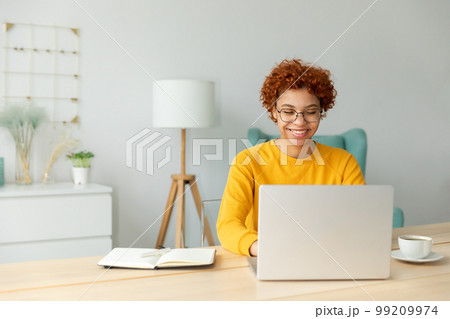 African american girl using laptop at home office looking at screen typing chatting reading writing email. Young woman having virtual meeting online chat video call conference. Work learning from home 99209974