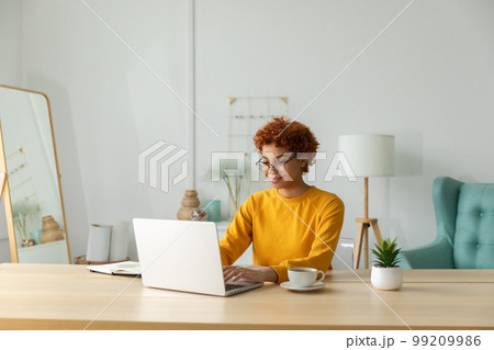 African american girl using laptop at home office looking at screen typing chatting reading writing email. Young woman having virtual meeting online chat video call conference. Work learning from home African american girl using laptop at home office looking at screen typing chatting reading writing email. Young woman having virtual meeting online chat video call conference. Work learning from home 99209986