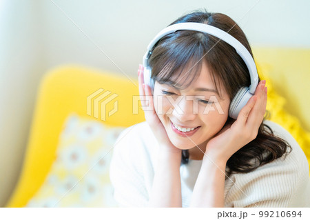 ヘッドホンで音楽を聴くミドルの女性 99210694