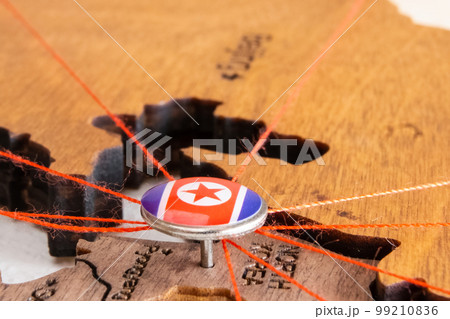 North Korea flag on the pushpin and red thread on the wooden map, close up. Mark of visiting places and planning of vacation and travel routes. North Korea flag on the pushpin and red thread on the wooden map, close up. Mark of visiting places and planning of vacation and travel routes. 99210836