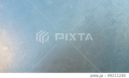 Abstract frosty pattern on glass, background texture. Frozen windshield. Granular structure of transparent ice. The sky is shining through. Abstract ice background. 99211280