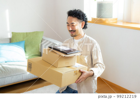リビングでたくさんの荷物を持つ男性（伝票は撮影のために作成したダミーです） 99212219