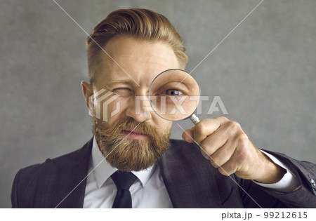 Portrait of a businessman in search of a solution looking through a magnifying glass Portrait of a businessman in search of a solution looking through a magnifying glass 99212615