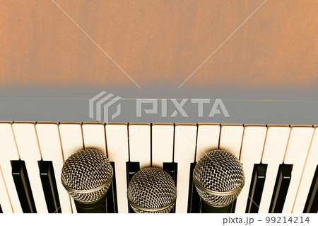 Vocal microphones for karaoke on synthesizer piano keys on a wooden surface Vocal microphones for karaoke on synthesizer piano keys on a wooden surface 99214214