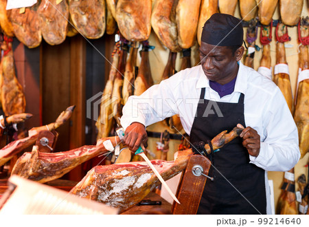 Salesman cutting delicious ham in butcher shop Salesman cutting delicious ham in butcher shop 99214640