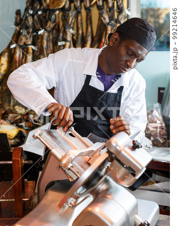 Butcher slicing jamon on machine 99214646