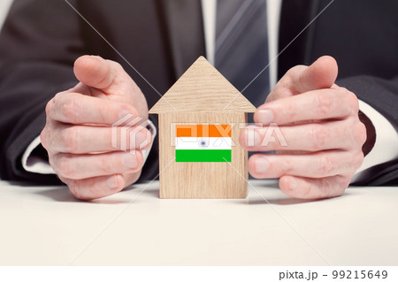 Businessman hand holding wooden home model with Indian flag. insurance and property concepts Businessman hand holding wooden home model with Indian flag. insurance and property concepts 99215649