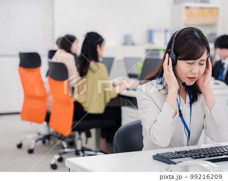 電話対応で疲労するお客様センターの女性 電話対応で疲労するお客様センターの女性 99216209