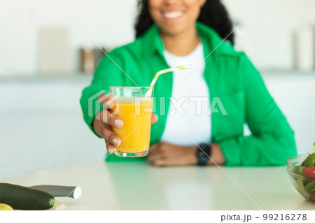 Unrecognizable Black Woman Offering A Glass Of Juice In Kitchen Unrecognizable Black Woman Offering A Glass Of Juice In Kitchen 99216278